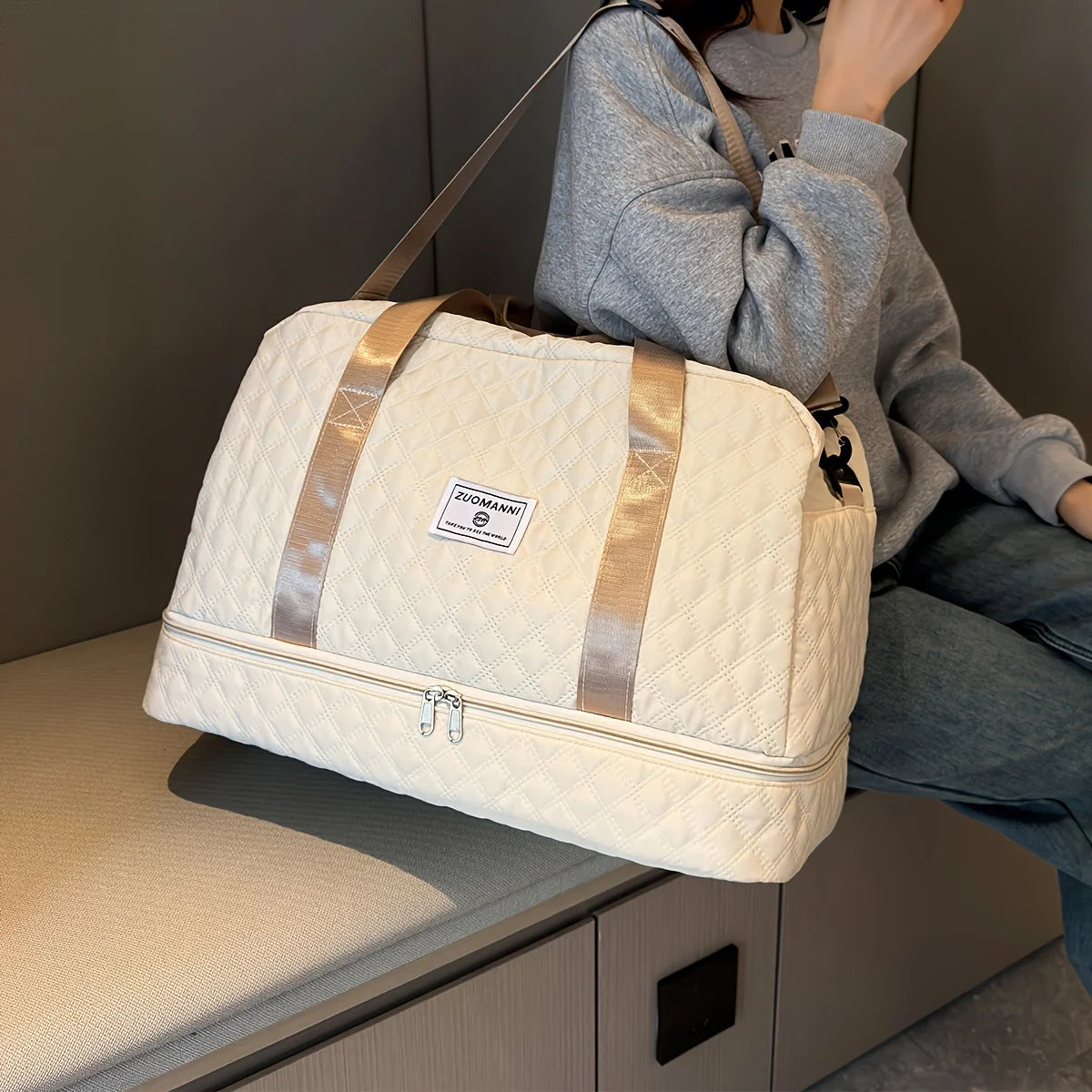 Quilted cream duffel bag with beige straps, Elarose style, on bench next to woman in grey sweater