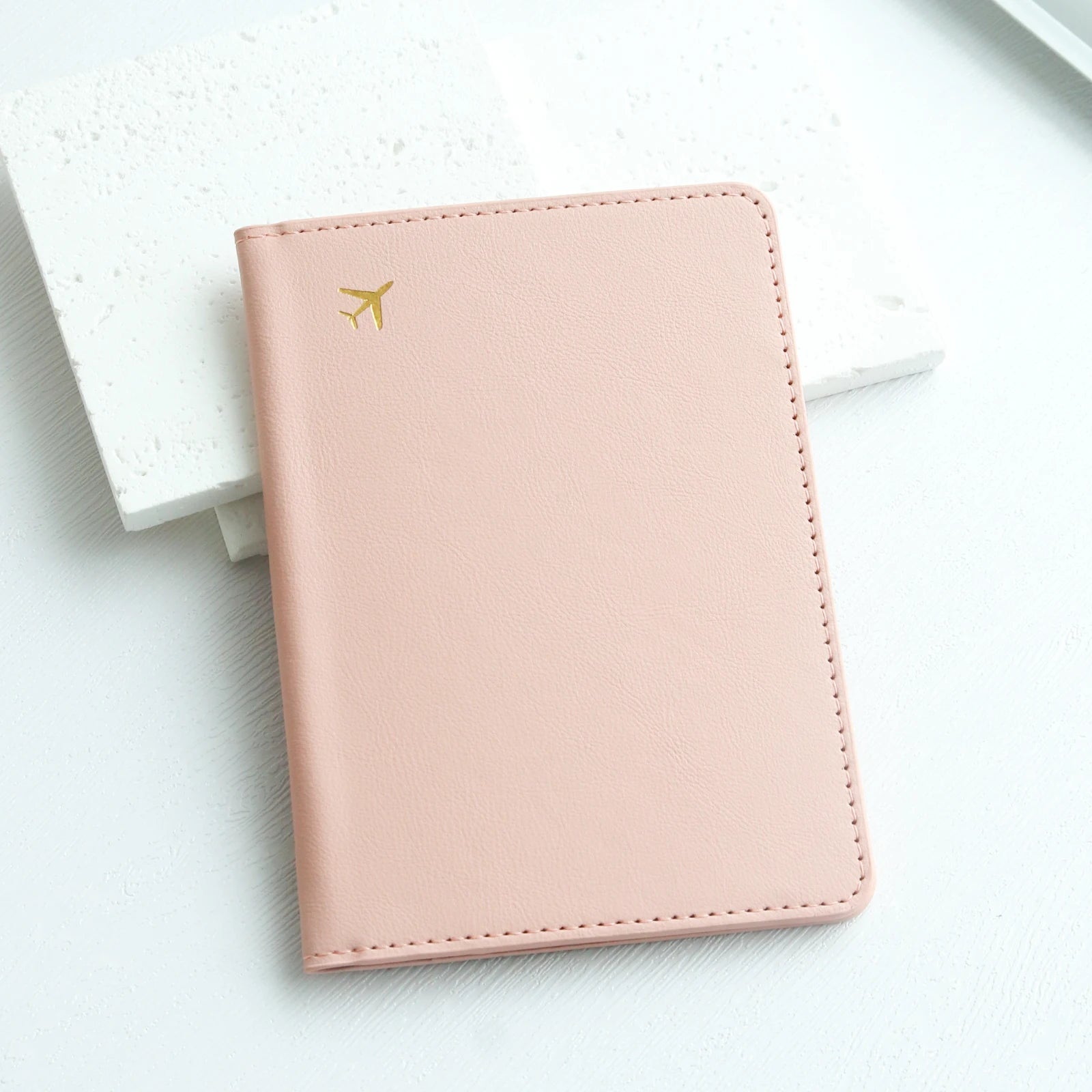 Elarose pastel pink passport holder with gold airplane icon on white background