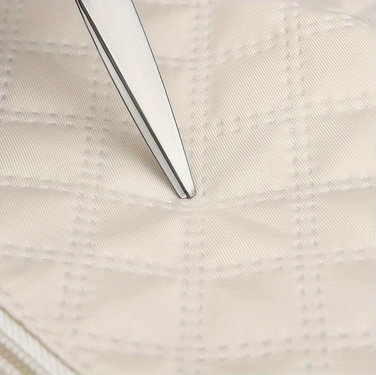 Tweezers pointing at quilted cream fabric with diamond stitching, Elarose detail