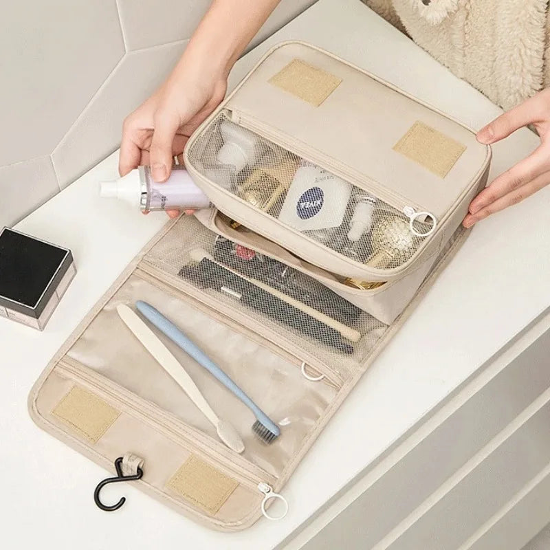 Beige travel toiletry bag with mesh pockets organized with toiletries on a bathroom counter