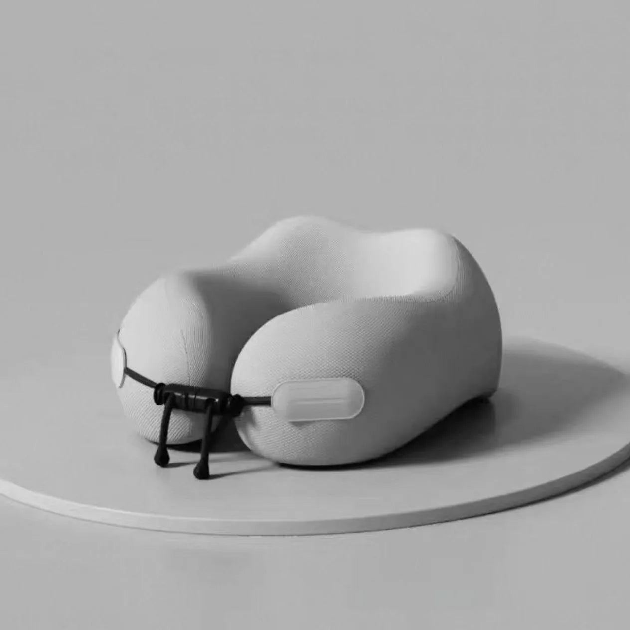 Elarose memory foam travel neck pillow in light grey on round platform, minimalist background